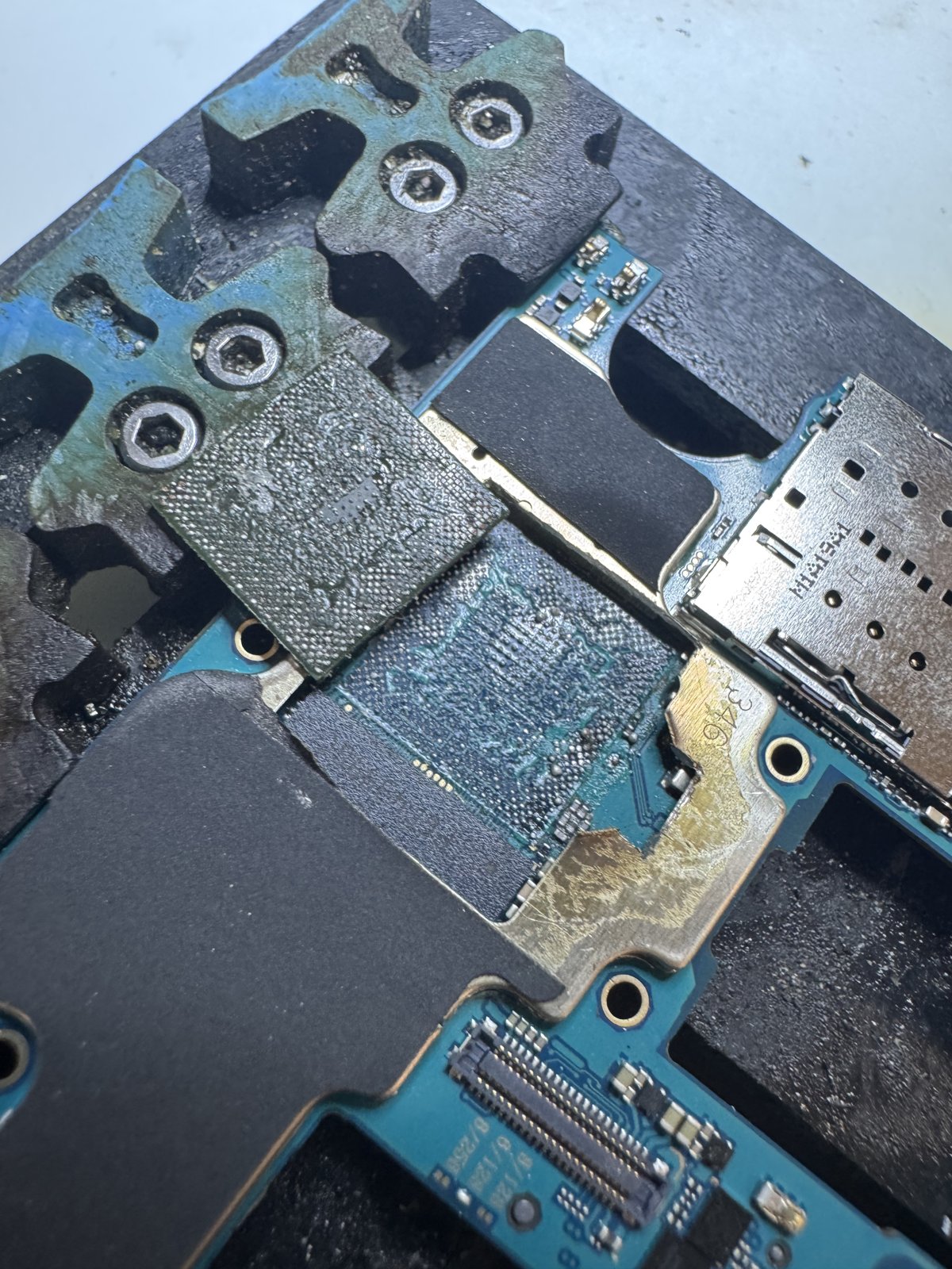 CPU取り外し後のGalaxy A52の基板と、脇に置いた取り外したチップ